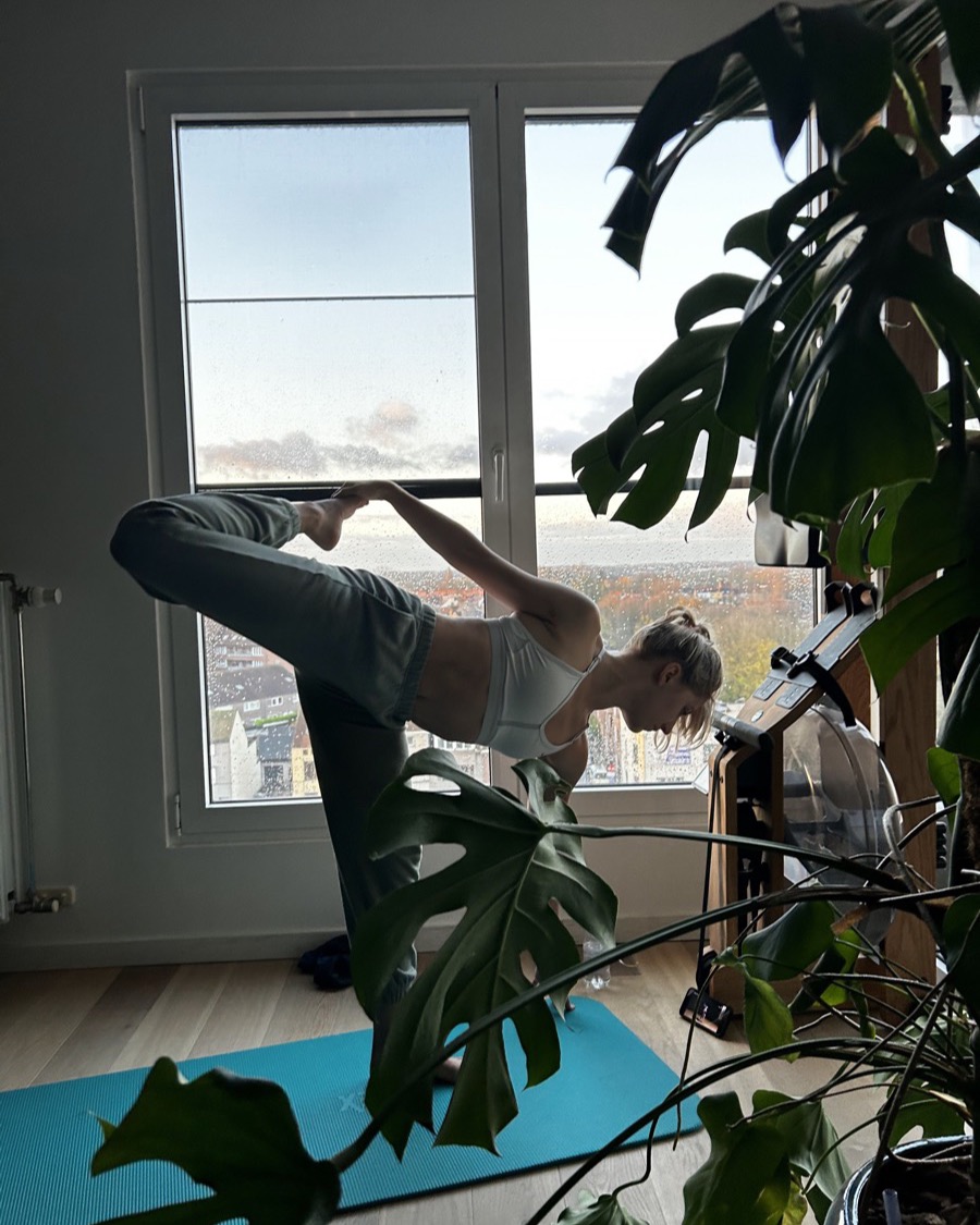 Elaine holding a standing balance pose on a mat at home